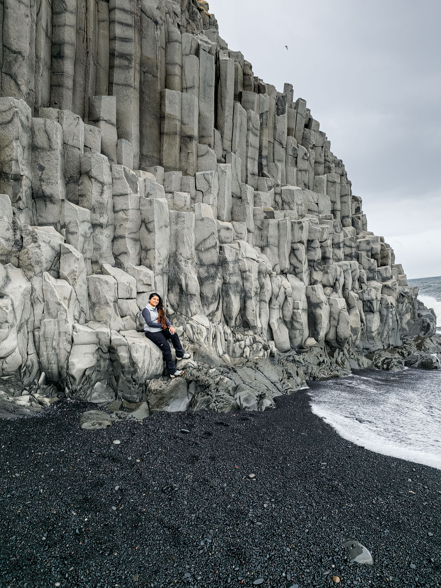 Sitting on the basalt stacks Reynisfjara Black Beach on Arctic Adventures South Shore Adventure Tour